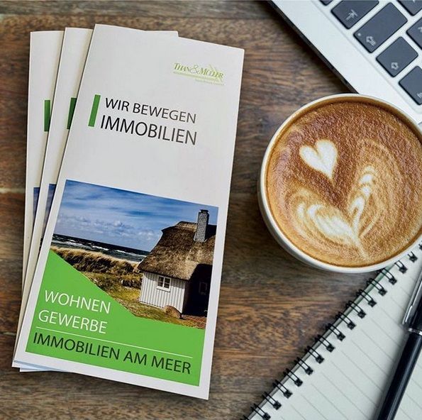 Than & Müller Immobilien Flyer auf einem Tisch